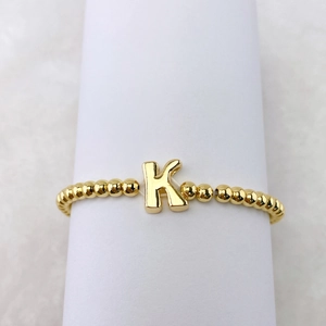Detailansicht eines 18k vergoldeten Perlenarmbands mit einem K-Buchstabenanhänger