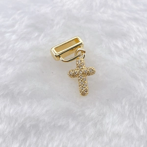 Detailed view of a gold-plated cross charm with sparkling crystals for watch bands