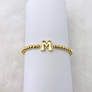 Nahaufnahme von 18k vergoldetem Perlenarmband mit einem 3D-Buchstaben M Anhänger