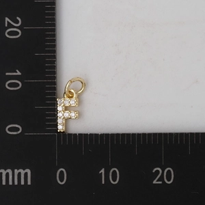Dettaglio macro del ciondolo lettera F dorata con zirconi e misura di 10mm indicata