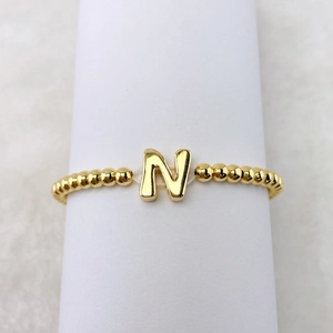 Detailansicht eines 18k vergoldeten elastischen Perlenarmbands mit glänzendem Buchstaben-N-Anhänger