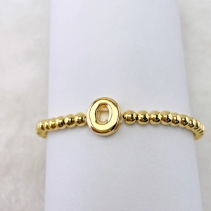 Detail eines 18k Goldperlen-Armbands mit einem polierten 3D-Buchstaben-O-Anhänger