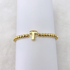 Nahaufnahme eines vergoldeten Perlenarmbandes mit einem glänzenden 18k 3D-Buchstabe T Anhänger
