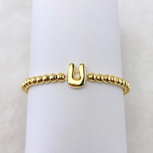 Makroaufnahme eines 18k Goldperlenrings mit poliertem Buchstaben-U-Anhänger im Detail