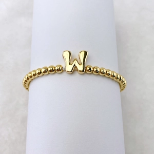 Detail eines 18k vergoldeten Perlenarmbandes mit einem markanten Buchstaben-W-Anhänger