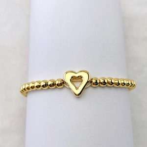 Nahaufnahme des goldenen Perlenarmbands mit hohlem Herzanhänger auf weißem Ständer