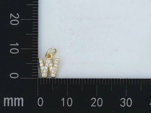 Macro di ciondolo lettera W dorata con zirconi incastonati accanto a una scala metrica