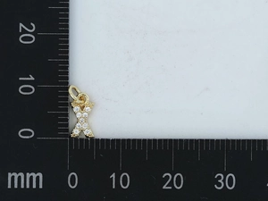 Macro del ciondolo a lettera X dorata con zirconi che mostra la misura esatta di 10 mm