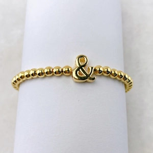 Detailaufnahme des 18k vergoldeten Perlenarmbands mit glänzendem Et-Zeichen-Anhänger