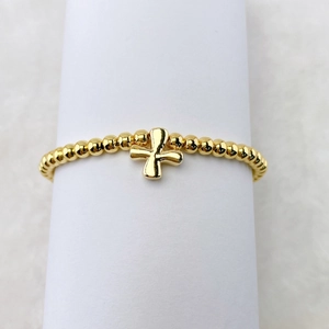 Nahaufnahme eines vergoldeten Perlenarmbandes mit einem kleinen Kreuzanhänger