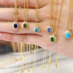 Oval birthstone pendant necklaces with gold plating and surrounding cubic zirconia stones