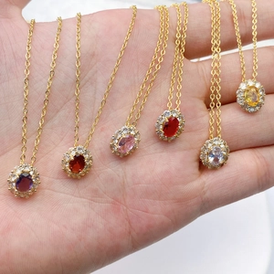 Hand holding colorful oval birthstone necklaces with halo cubic zirconia and gold chains