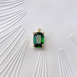 Macro detail of emerald-cut green stone pendant with golden star-shaped prongs