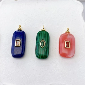 Detail of stone pendants in blue, green and pink with gold inlay and crystal on stone background