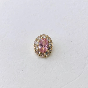 Macro detail of oval pink birthstone pendant with pavé cubic zirconia in gold plating