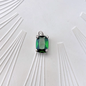 Detail view of emerald green square zircon pendant with silver claw setting and small crystals