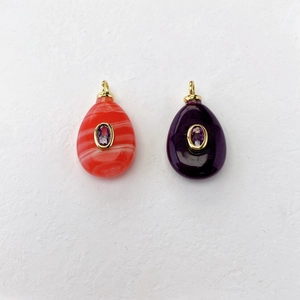 Detail view of water-drop pendants with orange and purple textures and inlaid gemstones