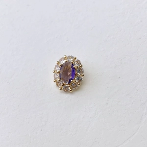 Macro detail of oval purple gemstone necklace pendant with halo of white zircons