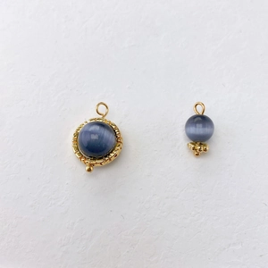 Detail showing blue cat-eye stone pendants with golden textured bezels and retro design