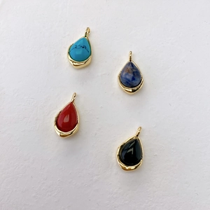 Detail view of four teardrop gemstones with gold plating in turquoise and agate