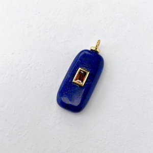 Macro shot of rectangular lapis lazuli pendant with gold trim and red gemstone center