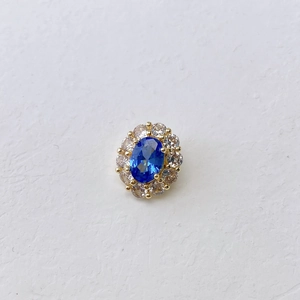 Macro shot of oval blue gemstone pendant with halo of zircons on a gold-plated base