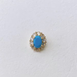 Detailed view of an oval blue birthstone pendant with sparkling zircon halo in gold plating