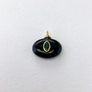 Close-up of a black oval pendant with a marquise green gemstone in golden metal frame