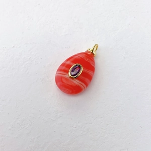 Macro detail of teardrop agate pendant with purple gemstone and gold bezel setting