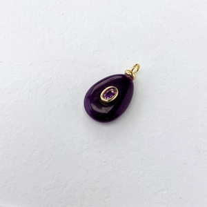 Detailed close-up of a drop-shaped deep purple gemstone pendant with a gold metal frame