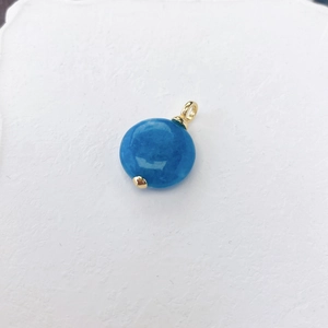 Macro-opname van een ronde blauwe natuursteen hanger met een gouden metalen oogje