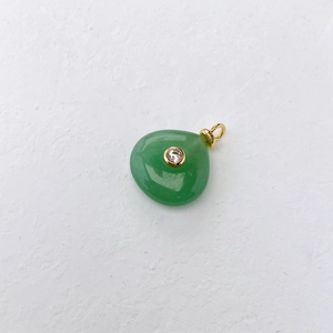 Macro view of green teardrop pendant with white zircon in gold setting detail
