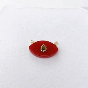 Detail of red eye-shaped agate pendant with gold rings and green teardrop stone