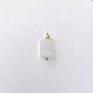 Detailweergave van rechthoekige witte agaat hanger met gouden oog op witte achtergrond
