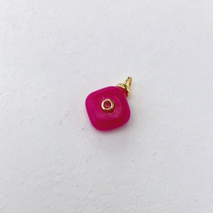 Close-up of rose red square pendant with gold circle inlay on white textured background
