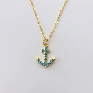 Dettaglio della collana con ciondolo ad ancora dorata con pietre blu e catena fine