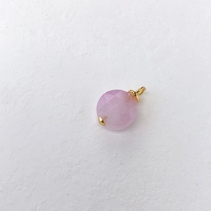 Detailopname van een gefacetteerde roze kristallen hanger met gouden haak op wit