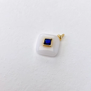 Macro shot of square pendant with blue gemstone inlay and golden metal frame detail