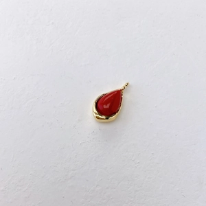 Detailed view of teardrop-shaped red gemstone pendant with polished gold bezel setting