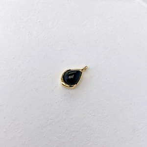 Macro shot of a teardrop-shaped black onyx pendant with a vintage gold-plated bezel setting