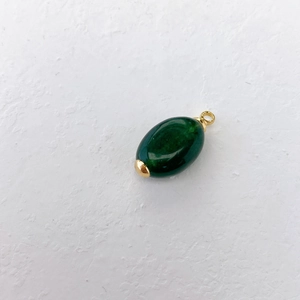 Gedetailleerd overzicht van een ovale donkergroene stenen hanger met gouden metalen accenten