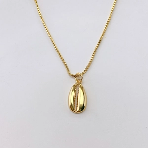 Dettaglio di una collana a catena box dorata con un ciondolo a conchiglia minimalista