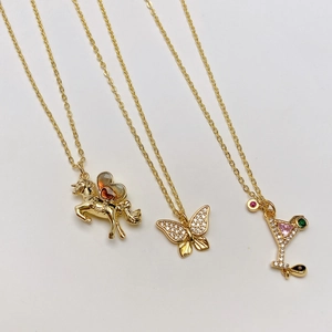 Detalle de collares dorados con colgantes de unicornio, mariposa de cristal y copa martini