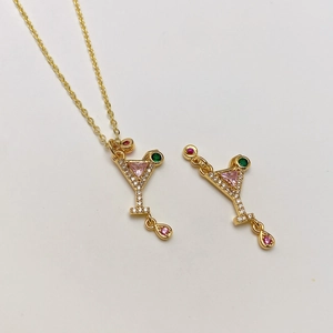 Detalle del colgante de copa de cóctel dorado con gemas rosas y piedra en forma de gota