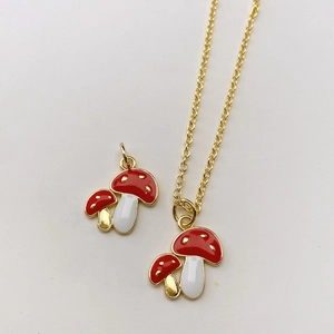 Nahaufnahme des goldenen Pilzanhängers mit roter Emaille und zarter Halskette