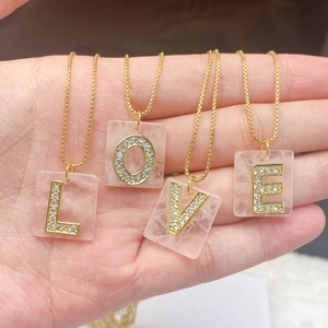 Detailansicht von vier Anhängern aus rosa Kristall mit gold eingelegten LOVE-Buchstaben