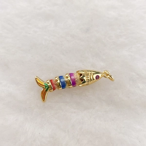 Macro shot of flexible colorful enamel tropical fish pendant with golden metal scales