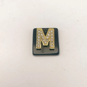 Makro-Detail von Naturstein-Quadrat-Anhänger mit Gold-Mikropavé-Buchstabe M Charme