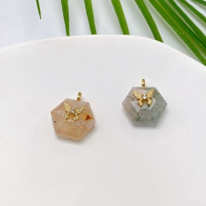 Hexagonal natural stone pendant with gold butterfly and crystal inlay on white plate