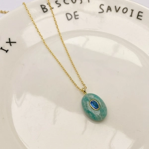 Vue détaillée d'un collier en chaîne dorée avec pierre naturelle verte et zircon bleu
